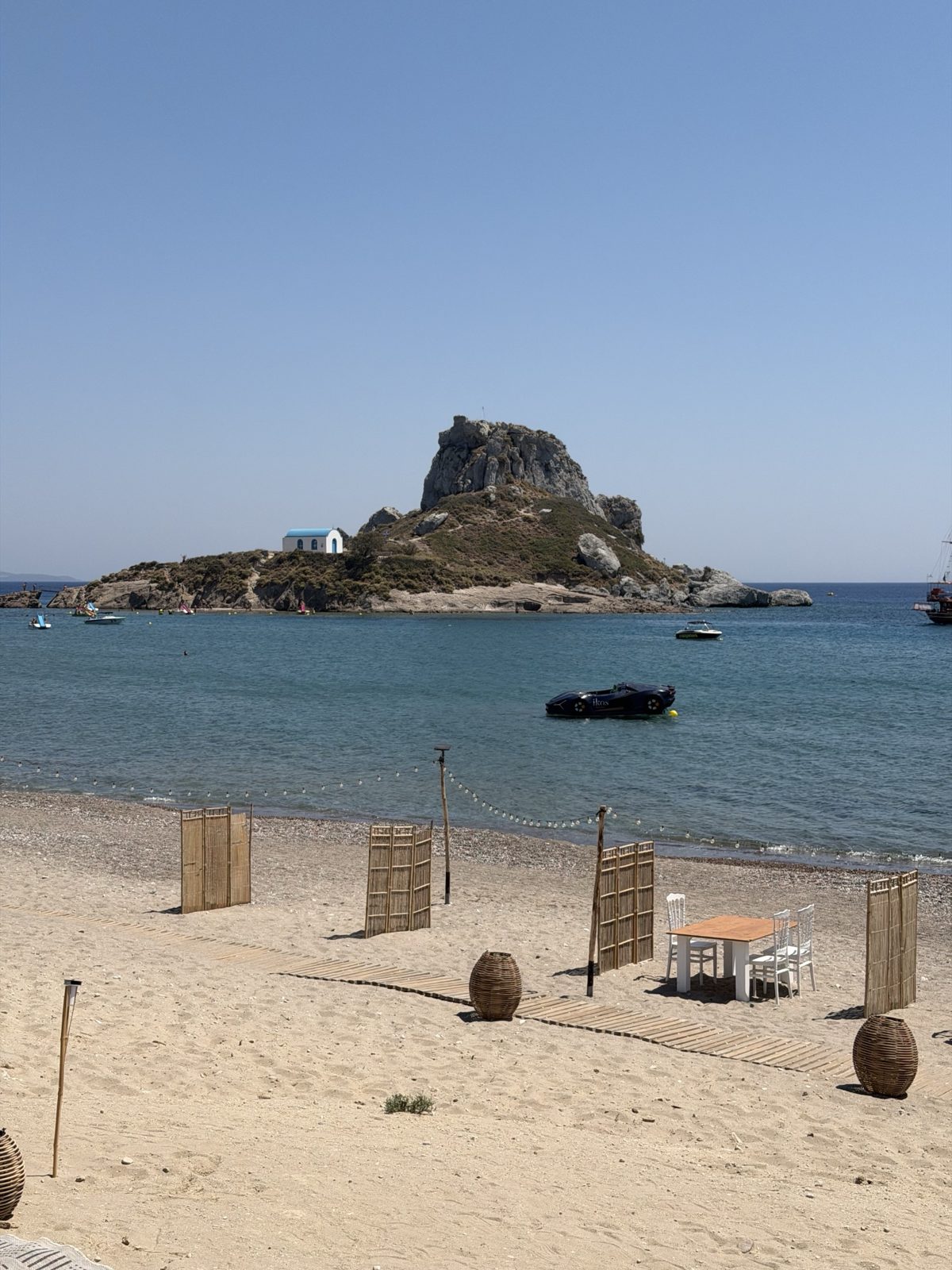 La spiaggia di Ikos Aria con l'isolotto di Kastri e la chiesetta bianca e blu