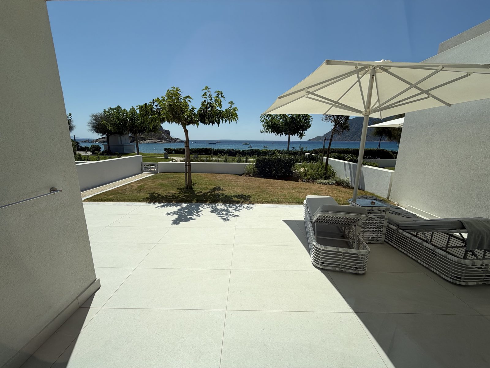 La terrazza della suite fronte mare di Ikos Aria con lettini e ombrellone